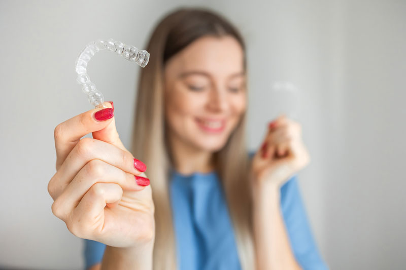 a woman holding an Invisalign cleat aligner